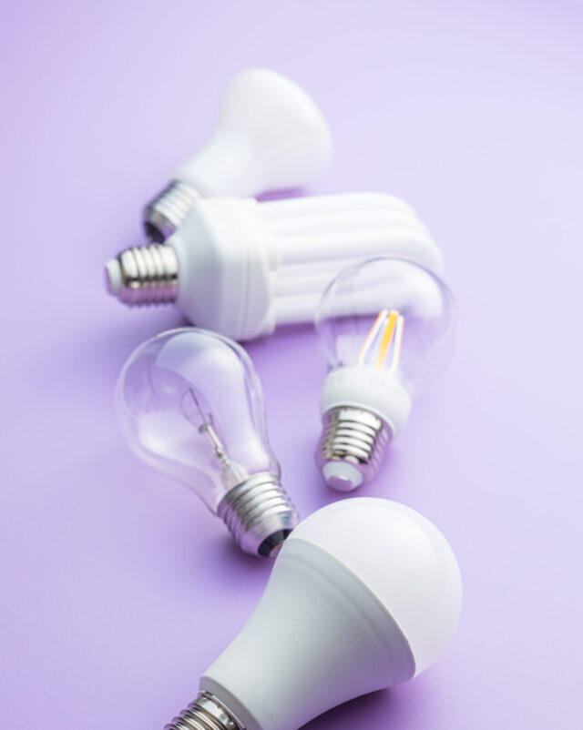 Energy saving and classic light bulbs on violet background.